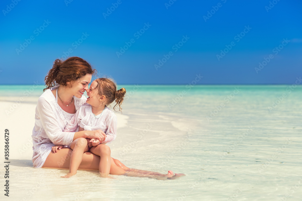 Mother and little daughter enjoy sunny beach on Maldives
