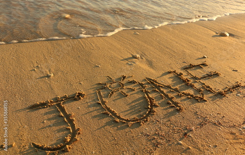 Wallpaper Mural JuneHand Written on Sandy Texture at a Sunny Beach with Pebbles with Sea Water in the Background. Travel in the Summer Months Tourism Wallpaper Image. Seascape Vacation Concept. Torontodigital.ca