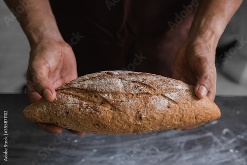 Baker or cooking chef holding freshly baked bread on hands after bake.