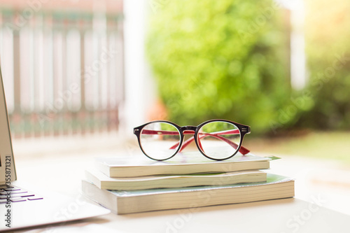 Glasses on the book blurred garden in home.