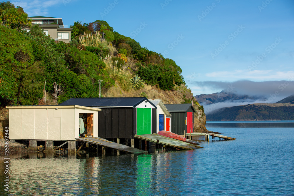 Colorful Boat Sheds with beautiful reflection on daytime  at Duvauchelle, Akaroa Harbour on Banks Peninsula in South Island, New Zealand.
