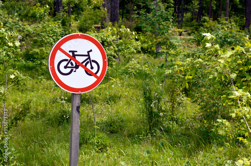 Bicycle prohibition sign on a green trees and grass background in park