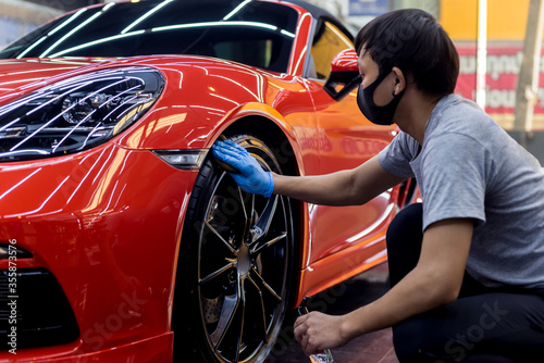 Car service worker polishing car wheels with microfiber cloth.