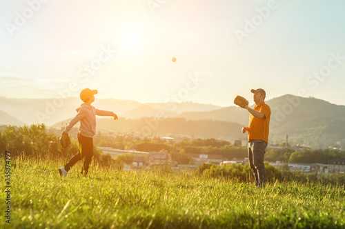 Father and son playing in baseball. Playful Man teaching Boy baseballs exercise outdoors in sunny day at public park. Family sports weekend. Father's day. photo