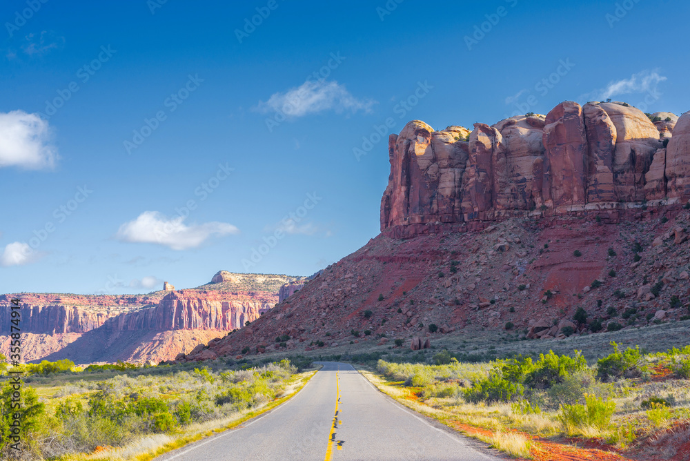 Fototapeta premium The road running through the dry prairie and rests on the red mountain.