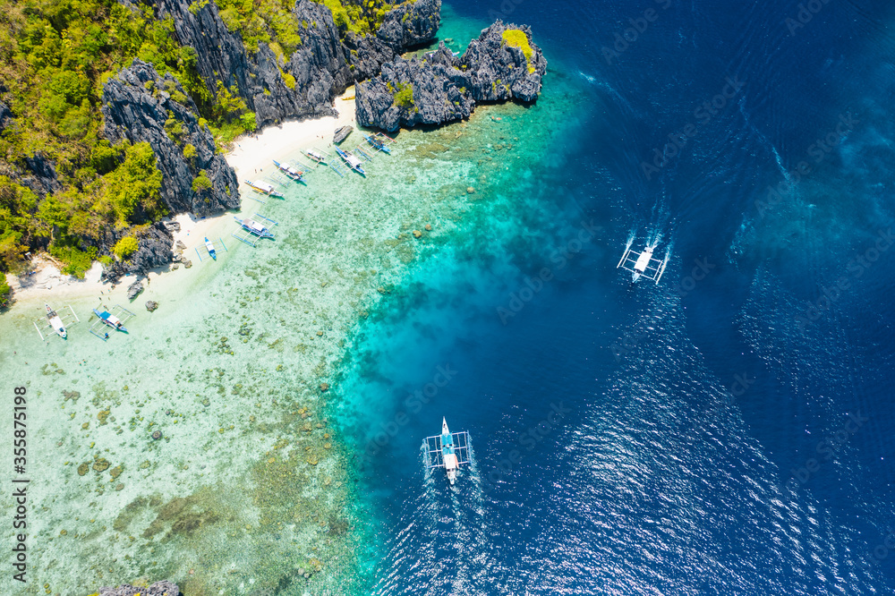 Shimizu Island, El Nido, Palawan, Philippines. Aerial drone view of a tiny tropical island with beach, coral reef and sharp limestone cliffs