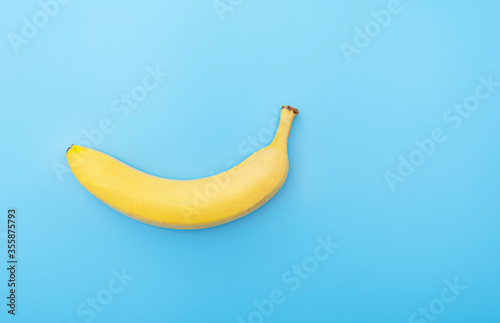 Creative picture of ripe fresh yellow banana on blue surface, table, background
