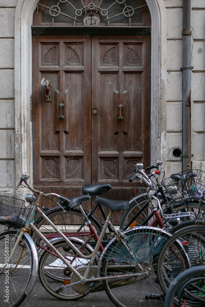 vertical photo of bicycles standing on the street against the background of an old wooden arched door vertical photo of bicycles standing on the street against the background of an old wooden arched door