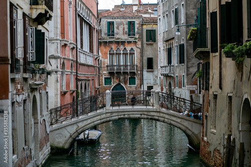 horizontal photo of a small concrete bridge over a venetian canal