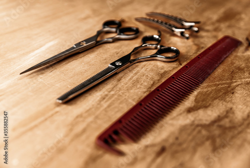 Hairdressing tools laid out on a wooden surface. Hairdressing comb and scissors. 