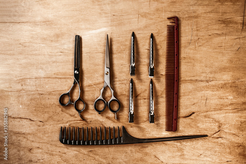 The hairdressing tool lies on a wooden board. Hairdressing combs and scissors.