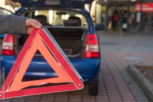 Red triangle warning sign and broken down car in the distance