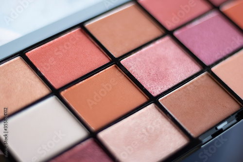 An eye shadow palette in an open container being prepared for a female make-up.