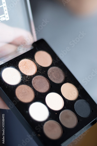 An eye shadow palette in an open container being prepared for a female make-up.