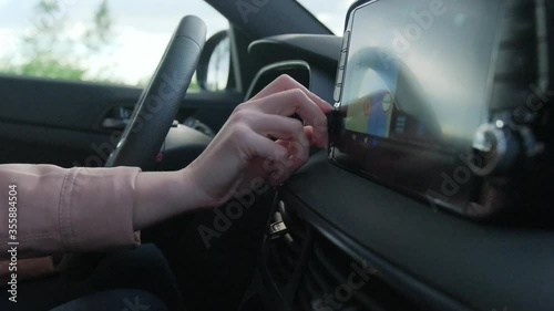 Woman hand, turning button on car radio for listening to music. The girl driving.