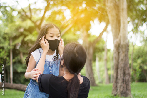 Mother wears a mask for the child in nature background