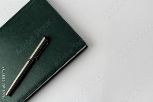 green notebook with pen on a white background