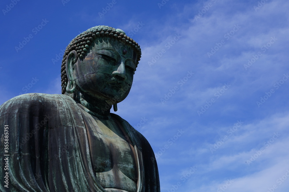 The Great Buddha of Kamakura is an outdoor bronze statue of Amida Buddha under blue sky located on the grounds of Kotoku-in Temple in Kanagawa Prefecture Japan. Kamakura Daibutsu Statue.