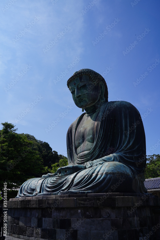 Obraz premium The Great Buddha of Kamakura is an outdoor bronze statue of Amida Buddha under blue sky located on the grounds of Kotoku-in Temple in Kanagawa Prefecture Japan. Kamakura Daibutsu Statue.