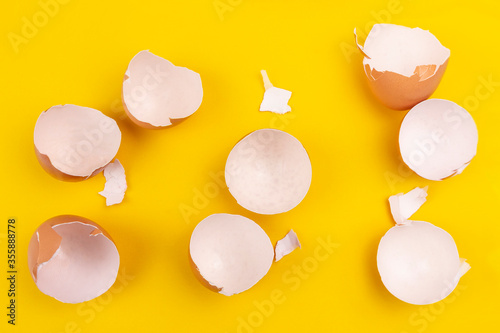 Empty broken brown egg shells on yellow background