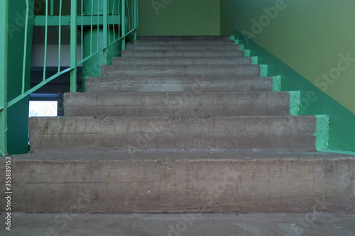 Gloomy concrete staircase in the entrance of an old multistory building. Dirty gray stairs and green walls. Low angle bottom view. Selective focus © ed2806