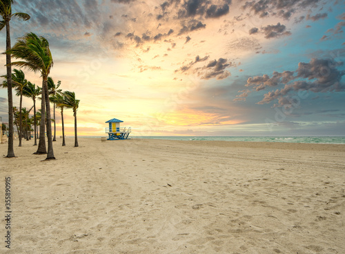 Fototapeta Naklejka Na Ścianę i Meble -  Dramatic sunrise on the beach with palm trees and lifeguard tower