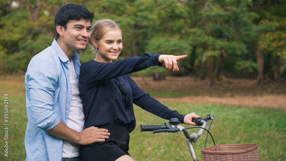 Young couple with bicycle walking in park on sunny day. Young couple with bicycle walking in park on sunny day.