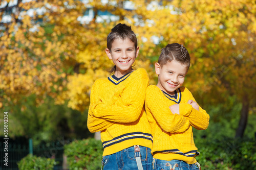 Two boys in the park standing back to back with crossed arms
