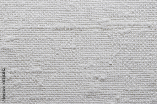 Texture of an old natural linen fabric with many defects. White textile material for background. Closeup