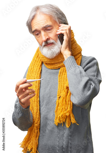 Ill elderly man with a digital thermometer in hand calling his doctor on the phone