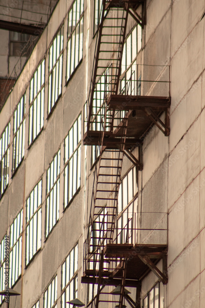 Fototapeta premium Close up of a rusty staircase on a building with large windows