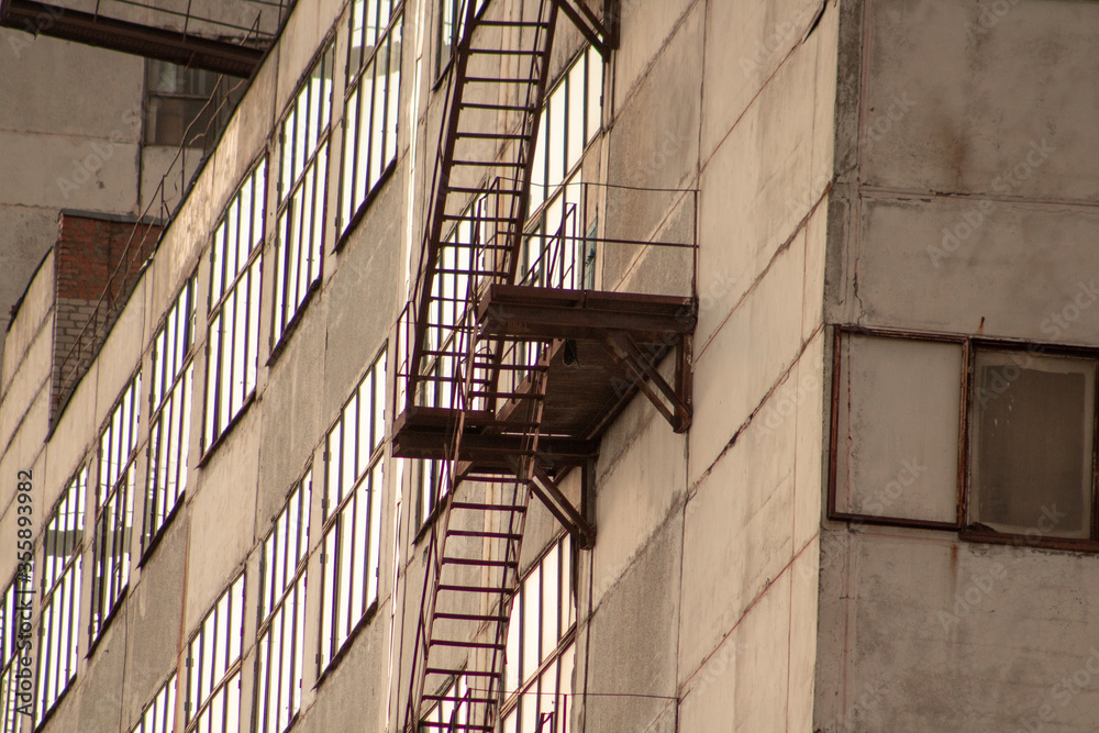 Fototapeta premium Close up of a rusty staircase on a building with large windows