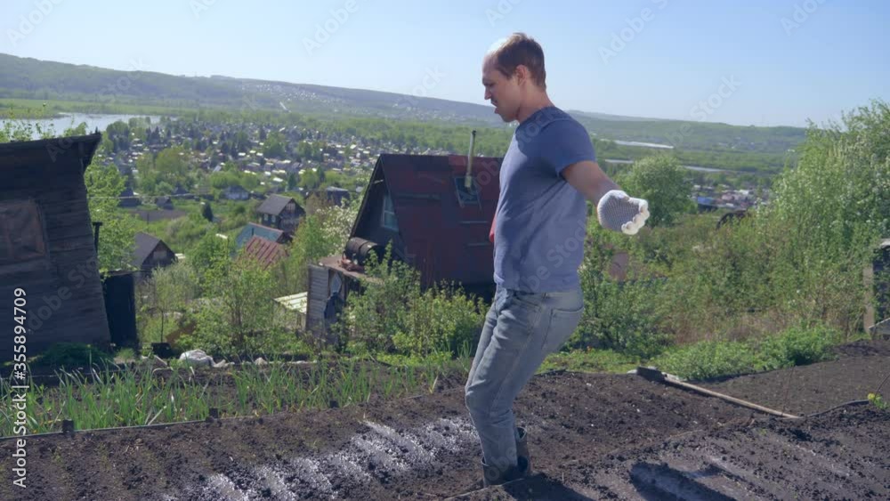 bald mustachioed man joyfully watering the garden with red watering can