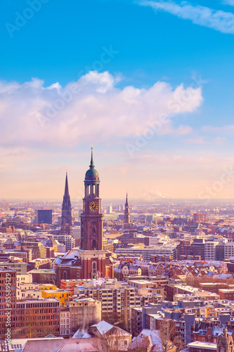 Scenic panorama view from Dancing Towers over Hamburg under snow in winter with St. Michael's Church (German: St. Michaelis) and city skyline at sunset.