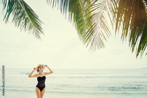 Vacation on the seashore.Young woman in hat and swimsuit relaxing on the beautiful tropical beach.