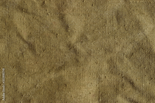 Old and crumpled khaki tarpaulin, detailed texture. Fabric of a vintage army military or travel backpack for background.  Worn natural sail cloth material. Closeup
