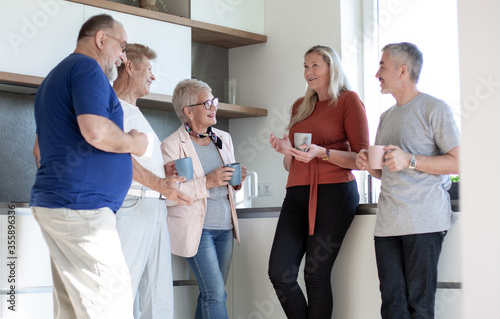 group of friends with cups of coffee standing in the home kitchen.