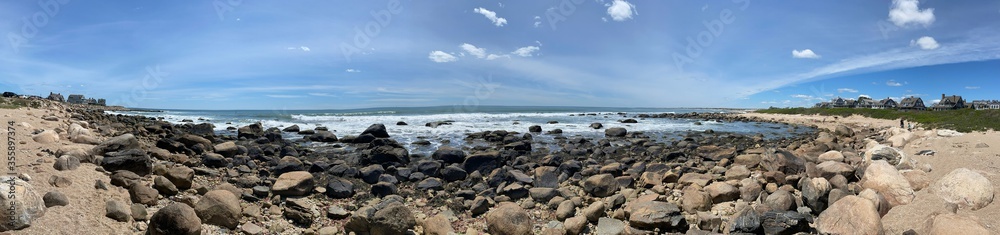 Panoramic view of a rocky beach in Weekapaug, Rhode Island on a sunny day with blue sky Panoramic view of a rocky beach in Weekapaug, Rhode Island on a sunny day with blue sky