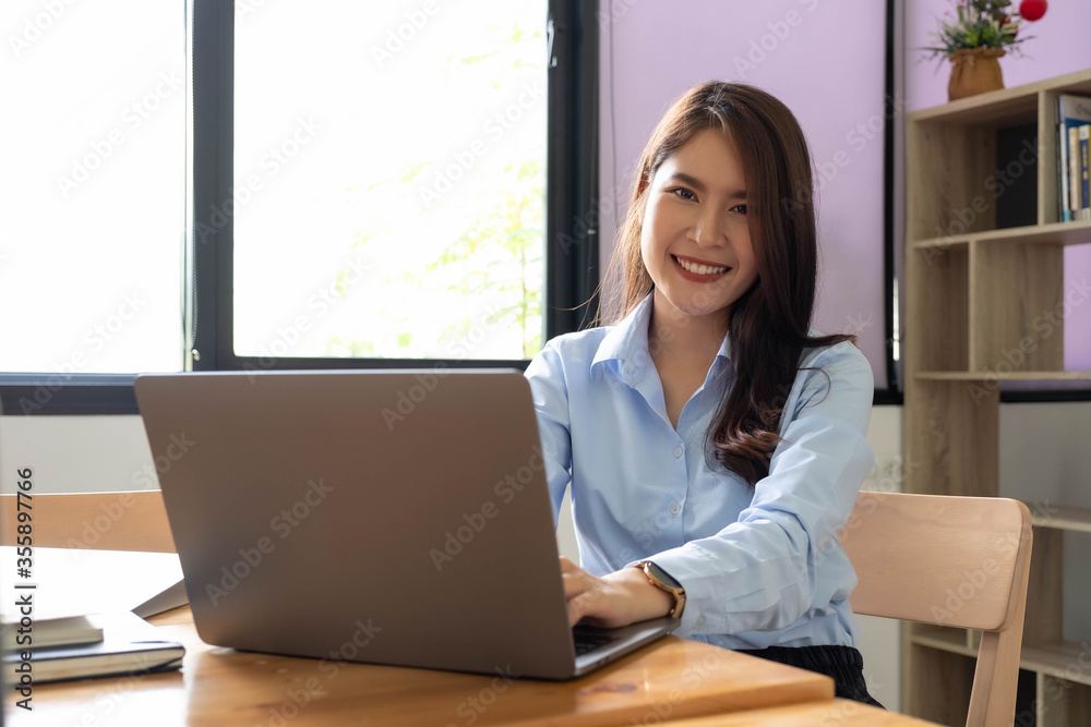 Portrait of young woman using laptop, she is working on laptop computer at a coffee shop Portrait of young woman using laptop, she is working on laptop computer at a coffee shop