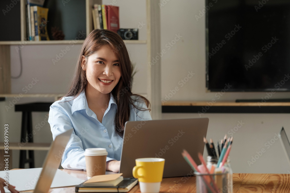 Portrait of young woman using laptop, she is working on laptop computer at a coffee shop Portrait of young woman using laptop, she is working on laptop computer at a coffee shop