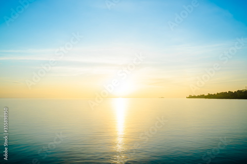 Front view in the indigo blue ocean in the morning, the sun was rising, reflections fell on the smooth calm surface with golden warm light.  The sky is clear and clean. Feeling refreshed and relaxed.