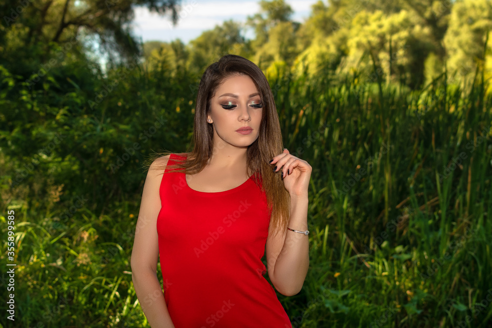 Beautiful woman in red dress with stylish makeup. Girl walking outdoors. Young lady with eyes closed Beautiful woman in red dress with stylish makeup. Girl walking outdoors. Young lady with eyes closed