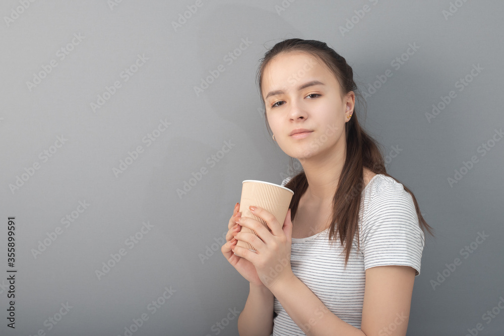Young woman drinks coffee on gray background Young woman drinks coffee on gray background