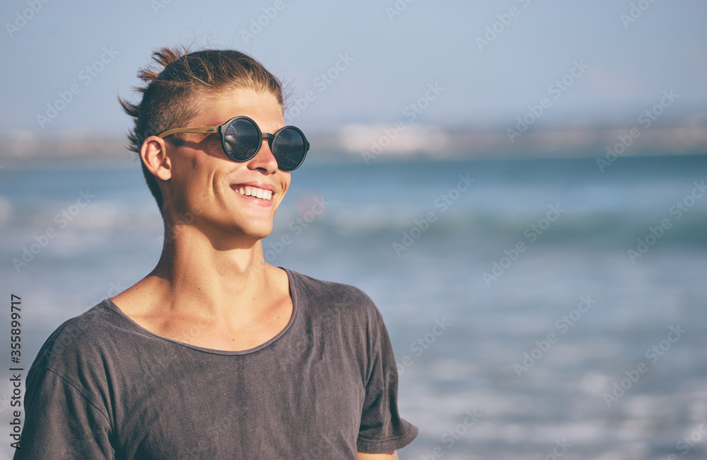Portrait of young handsome man on the sea shore. - obrazy, fototapety, plakaty 