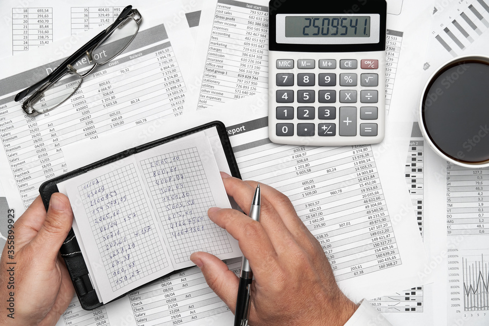 Top view of businessman working with financial statements. Modern black office desk with notebook, pencil and a lot of things. Flat lay table layout.