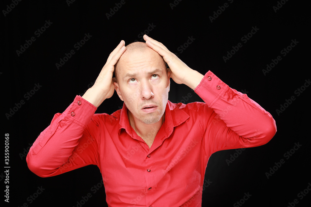 Adult caucasian bald man in red shirt showing how paining head isolated on black background Adult caucasian bald man in red shirt showing how paining head isolated on black background