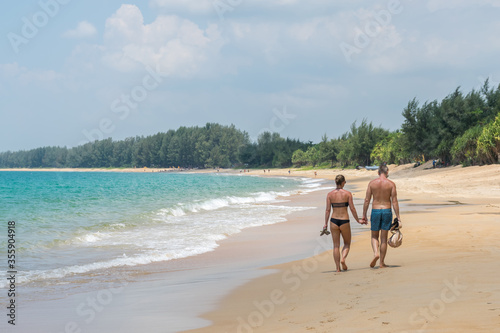Couple holding hands walking at white sand at tropical beach in Phuket island,Thailand