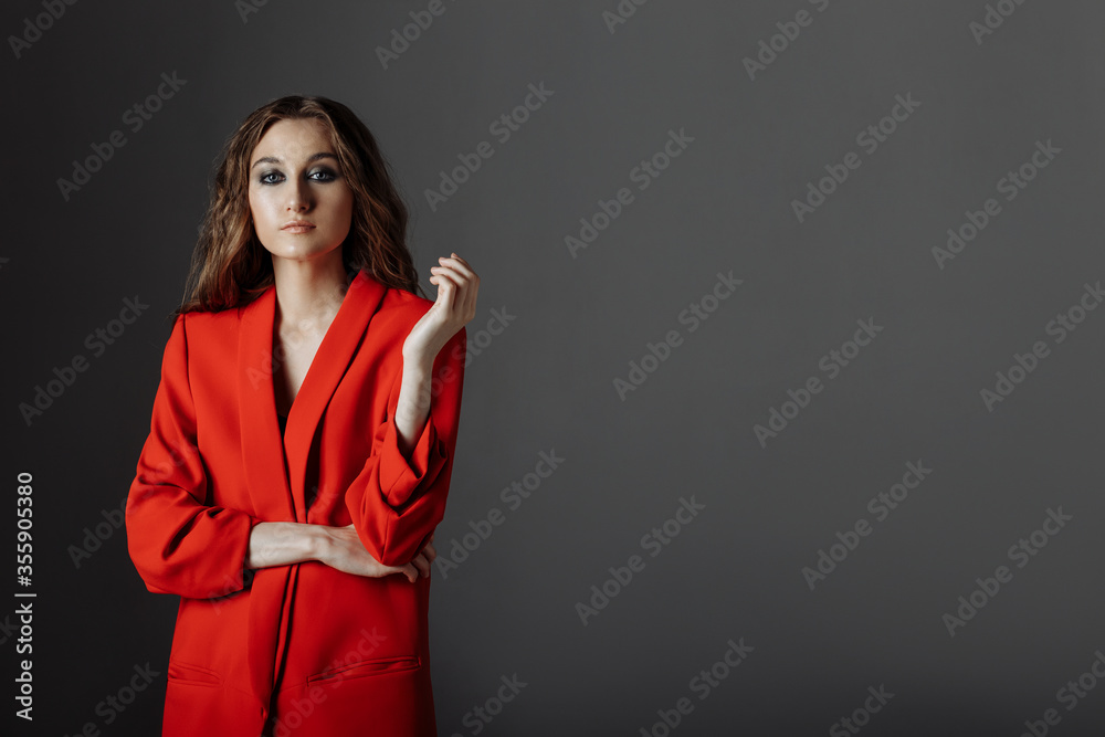 A business woman is very angry and shows her finger. Beautiful young serious woman in red suit, arrogant sexy successful businesswoman on gray background, isolated. Studio portrait A business woman is very angry and shows her finger. Beautiful young serious woman in red suit, arrogant sexy successful businesswoman on gray background, isolated. Studio portrait