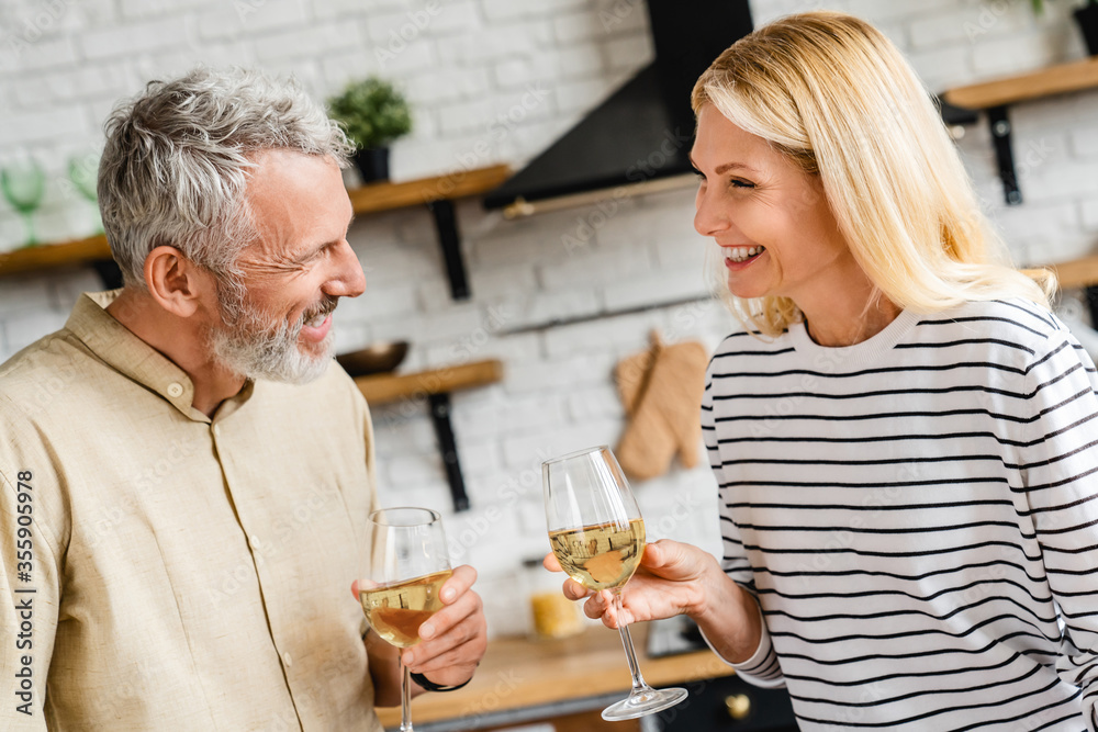 Relaxed senior couple in modern home with glass of wine celebrating