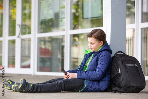 Photos Truancy concept, young boy staying away from the school and playing games on mob